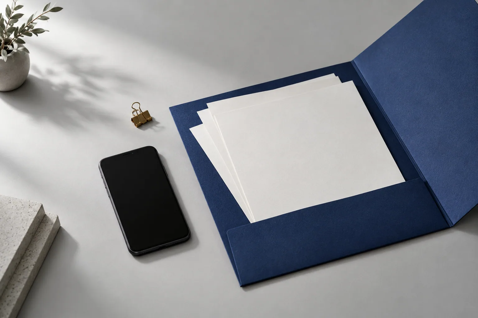 Composición editorial de una carpeta, documentos y un teléfono, como punto de partida de una solicitud.